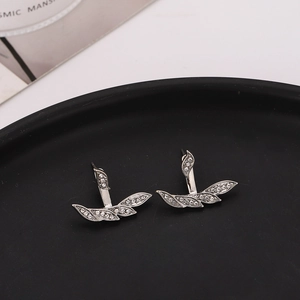 Macro shot of silver leaf earrings with rhinestone pave setting on a black surface