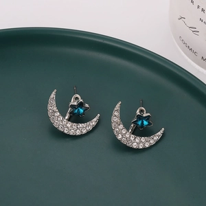 Detailed view of silver crescent moon stud earrings with blue star and sparkling stones