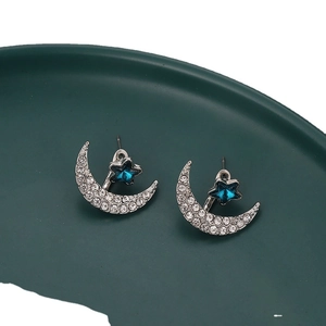 Star and moon studded earrings with blue crystal star and silver moon on green plate