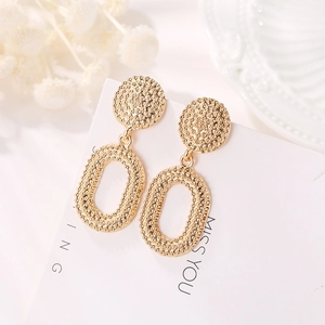 Close-up of golden vintage oval earrings with embossed dot texture on a display card