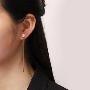 Orecchini di perle minimalisti con lunga catena in metallo indossati da una modella