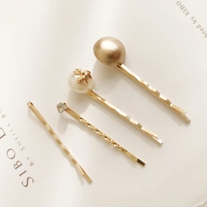 Detail view of a 4-piece golden hair clip set with pearls and rhinestones on a magazine