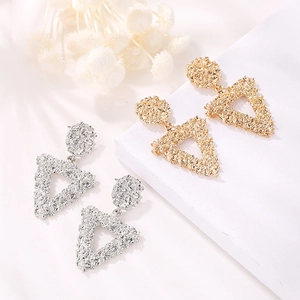 Textured gold and silver triangle drop earrings on a white elegant fabric surface