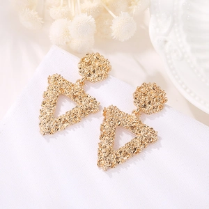 Detailed view of golden triangular earrings with textured metallic finish and geometric design