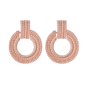 Dettaglio ravvicinato di orecchini a cerchio geometrici in oro rosa con trama a sfere di metallo