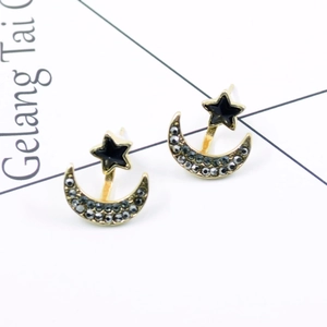 Macro view of asymmetric star and moon earrings with gold finish and black inlay