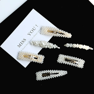 Elegant gold pearl hair clips set with white imitation pearls on a black background