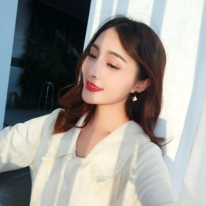 Minimalist geometric gold and black rhombus drop earrings worn by a female model