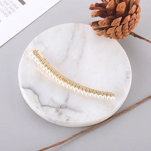 Detail of gold metal hair clip featuring white pearls and sparkling rhinestones