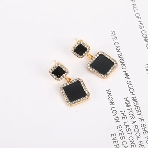 Detailed macro view of black enamel square earrings with gold-tone rhinestone border