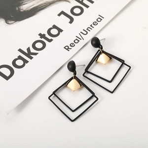 Macro view of geometric earrings with matte black frames and golden diamond pendants