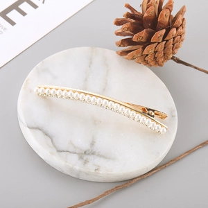 Elegant gold hair clip with pearls and rhinestones on marble tray decoration