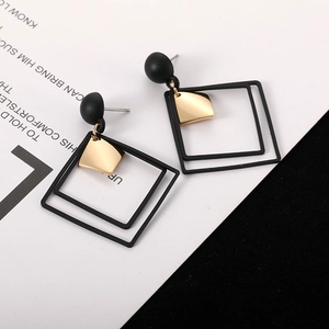 Macro detail of geometric black and gold square earrings with polished metal texture