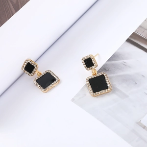 Detail of gold geometric square earrings with black enamel and sparkling rhinestones