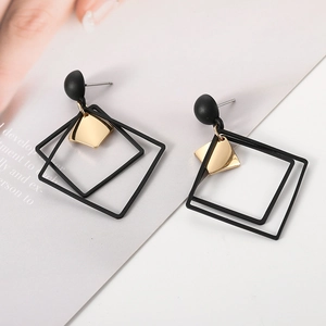 Detail view of geometric double square drop earrings with black frames and gold diamond charm