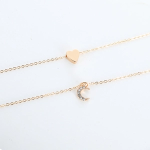 Close-up of gold-plated heart and moon pendant necklaces featuring white zircon stones