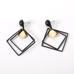 Detail of geometric square earrings in matte black and gold finish with minimalist style