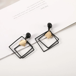 Detail of geometric rhombus dangle earrings with black matte spheres and gold square accents