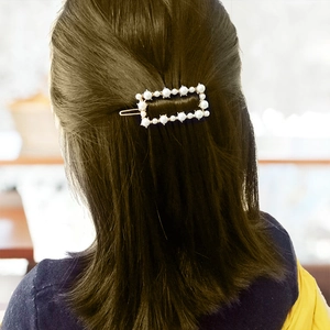 Eleganter rechteckiger Perlen-Haarclip mit Goldbasis auf dunkelbraunem Haar