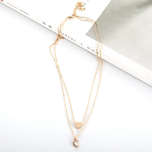 Detail of layered gold necklace with heart pendant and sparkling crescent moon charm