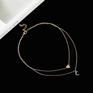 Multilayer gold necklace featuring a polished heart and crystal moon pendant on black background