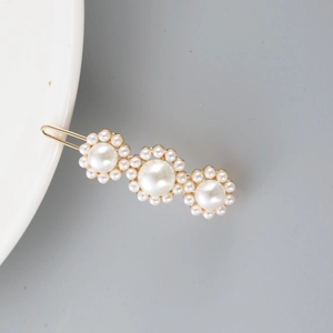 Detail of elegant gold alloy hair clip with three large white pearls and small beads
