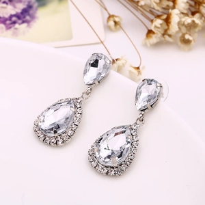 Macro shot of silver-tone teardrop zircon earrings with micro-pave crystals on white porcelain