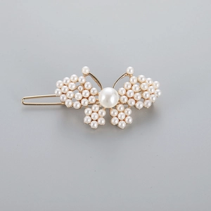 Detail view of a pearl butterfly hair clip featuring white pearls on a light gold frame