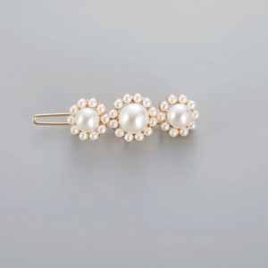 Detail showing three pearl floral clusters on a gold-plated geometric hair clip
