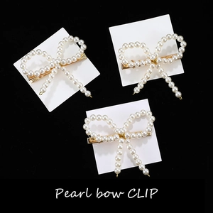 Détail de barrettes à cheveux nœud en perles avec base dorée et perles blanches tissées