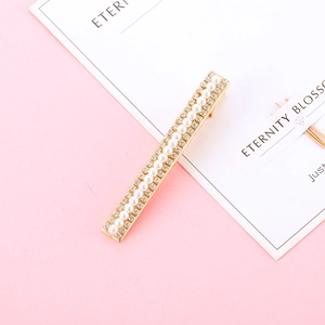Gros plan détaillé d'une pince à cheveux dorée ornée de perles et de strass brillants