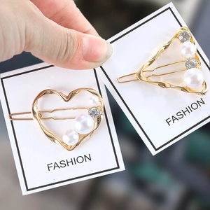 Détail de barrettes dorées géométriques avec perles blanches et strass sur carte de mode
