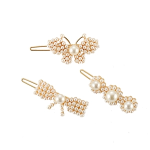 Detailed view of three pearl hair clips with butterfly and floral designs on gold alloy