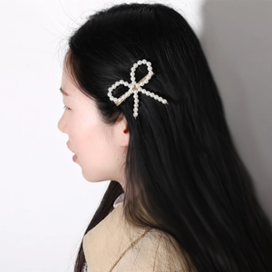 Barrette à cheveux avec nœud en perles sur modèle aux cheveux noirs et fond blanc
