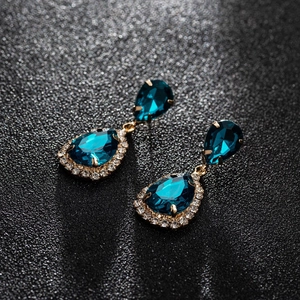 Detail of waterdrop pear-cut blue zircon earrings with sparkling halo in gold setting