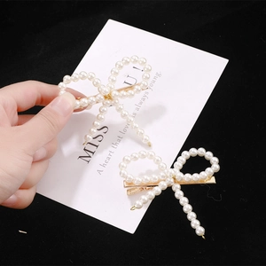 Lot de barrettes à cheveux perles et nœuds avec clips dorés sur fond noir