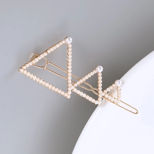 Détails d'une barrette dorée avec des perles et des formes de triangles géométriques