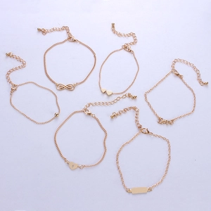 Detail view of 6-piece gold bracelet set with infinity, love, and heart charms on light background