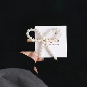 Détail d'une barrette à cheveux nœud en perles blanches avec support en métal doré
