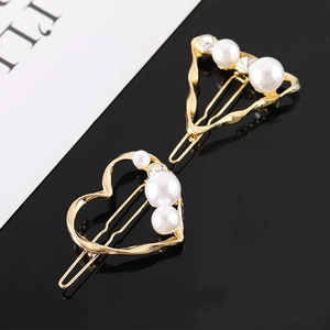 Détail de barrettes géométriques dorées avec perles ivoire et strass sur fond contrasté