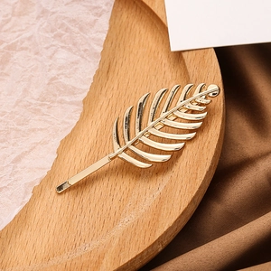 Élégante pince à cheveux en forme de feuille dorée sur un fond minimaliste chic