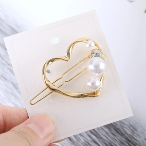 Détail de la pince à cheveux cœur dorée avec perles et petit cristal étincelant