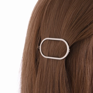 Pinza para el pelo ovalada plateada minimalista con acabado de metal pulido en pelo castaño