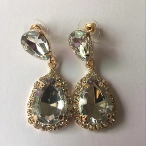 Detail of gold drop earrings featuring sparkling teardrop crystals and micro-pavé setting