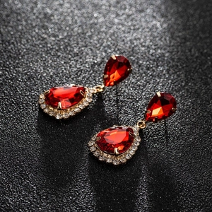 Macro detail of red pear-cut zircon earrings with gold plating and halo stones