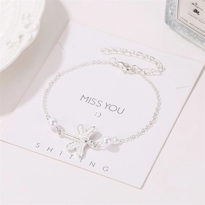 Detailed macro view of dragonfly anklet with silver chain and white pearl charms