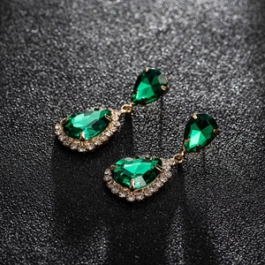 Detailed macro of vintage gold drop earrings with emerald green teardrop crystals