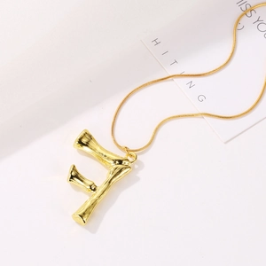 Goldene Halskette mit F-Anhänger und strukturierter Bambus-Optik auf Schlangenkette