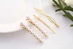 Vue détaillée de barrettes à perles dorées et épingles à strass dans un ensemble de luxe