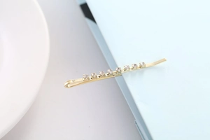 Gros plan détaillé d'une barrette dorée ornée de huit strass ronds et brillants